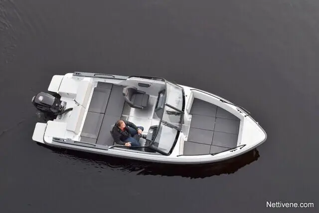 Aerial view of a motorboat on dark water, with a man seated at the helm, navigating the vessel.